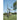 Person using a pitching machine on a grassy field with trees in the background