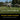 Woman runs with a football on a lawn near a house and trees