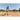 Baseball player swinging a bat on a field with another player in the background.