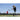 Baseball player swings bat at ball on field under clear sky with coach nearby