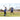 Player swings bat at ball during practice on a baseball field with coach watching