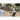 Girl with a bat prepares to swing in a fenced outdoor area during daytime