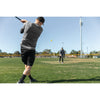 Man hitting SKLZ premium impact baseball with a golf club on a sunny day in a baseball field